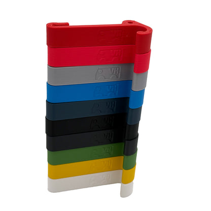 Ein robuster Multifunktionshaken in 10 verschiedenen Farben, eingehängt an einem Schrank im VW Grand California. Am unteren Haken hängt eine Jacke, während durch die kleine Öse auf der Rückseite eine Schnur gezogen ist, an der ein Bluetooth-Lautsprecher befestigt wurde. Der Haken fügt sich unauffällig ins Fahrzeugdesign ein und bleibt sowohl bei geöffnetem als auch geschlossenem Schrank nutzbar. Perfekt für mehr Ordnung im Camper!