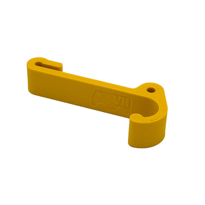 Ein robuster Multifunktionshaken in gelb, eingehängt an einem Schrank im VW Grand California. Am unteren Haken hängt eine Jacke, während durch die kleine Öse auf der Rückseite eine Schnur gezogen ist, an der ein Bluetooth-Lautsprecher befestigt wurde. Der Haken fügt sich unauffällig ins Fahrzeugdesign ein und bleibt sowohl bei geöffnetem als auch geschlossenem Schrank nutzbar. Perfekt für mehr Ordnung im Camper!