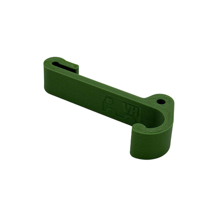 Ein robuster Multifunktionshaken in grün, eingehängt an einem Schrank im VW Grand California. Am unteren Haken hängt eine Jacke, während durch die kleine Öse auf der Rückseite eine Schnur gezogen ist, an der ein Bluetooth-Lautsprecher befestigt wurde. Der Haken fügt sich unauffällig ins Fahrzeugdesign ein und bleibt sowohl bei geöffnetem als auch geschlossenem Schrank nutzbar. Perfekt für mehr Ordnung im Camper!