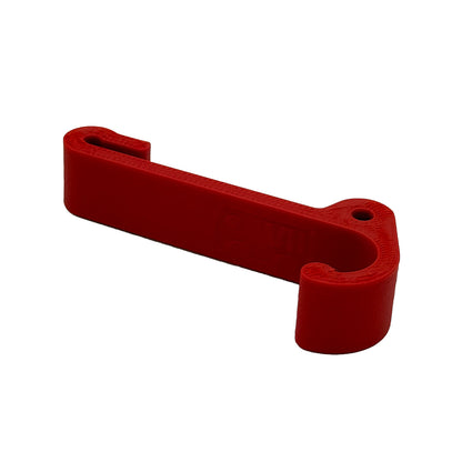 Ein robuster Multifunktionshaken in rot, eingehängt an einem Schrank im VW Grand California. Am unteren Haken hängt eine Jacke, während durch die kleine Öse auf der Rückseite eine Schnur gezogen ist, an der ein Bluetooth-Lautsprecher befestigt wurde. Der Haken fügt sich unauffällig ins Fahrzeugdesign ein und bleibt sowohl bei geöffnetem als auch geschlossenem Schrank nutzbar. Perfekt für mehr Ordnung im Camper!